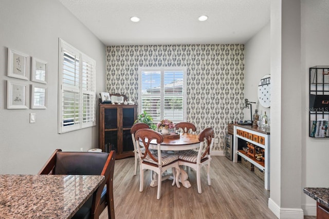 dining area with light hardwood / wood-style floors and a textured ceiling