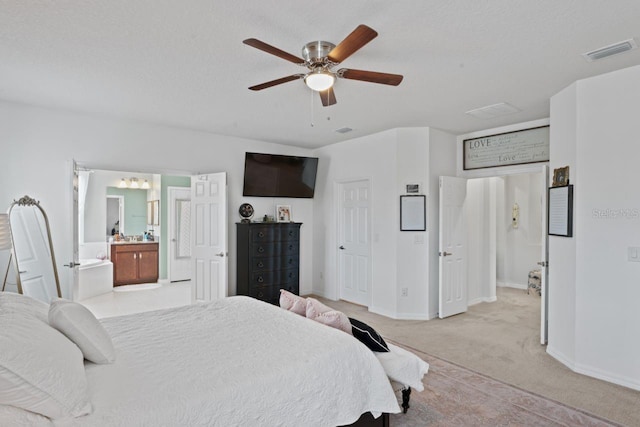 bedroom featuring ceiling fan, light carpet, ensuite bath, and a textured ceiling