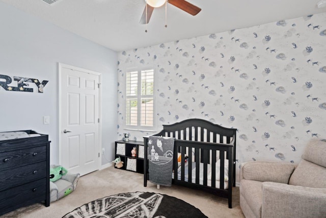 carpeted bedroom with a nursery area and ceiling fan