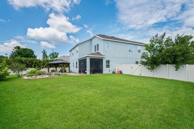 rear view of house with a yard, a sunroom, and a gazebo