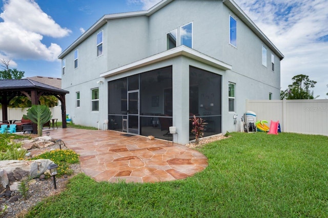 rear view of house with a patio area, a lawn, a sunroom, and a gazebo