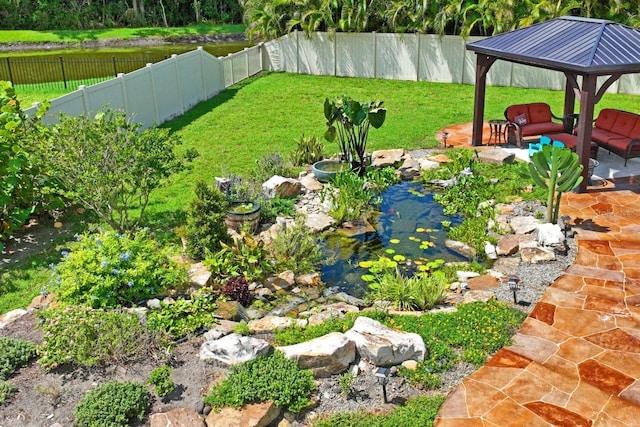 view of yard featuring a gazebo, outdoor lounge area, and a small pond