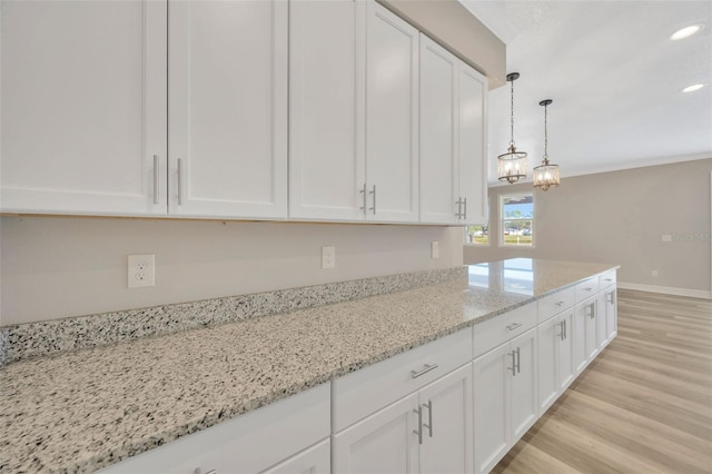 kitchen with white cabinetry, hanging light fixtures, light stone counters, and light wood-type flooring