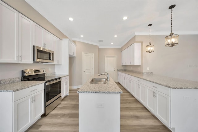 kitchen featuring appliances with stainless steel finishes, decorative light fixtures, white cabinetry, sink, and kitchen peninsula