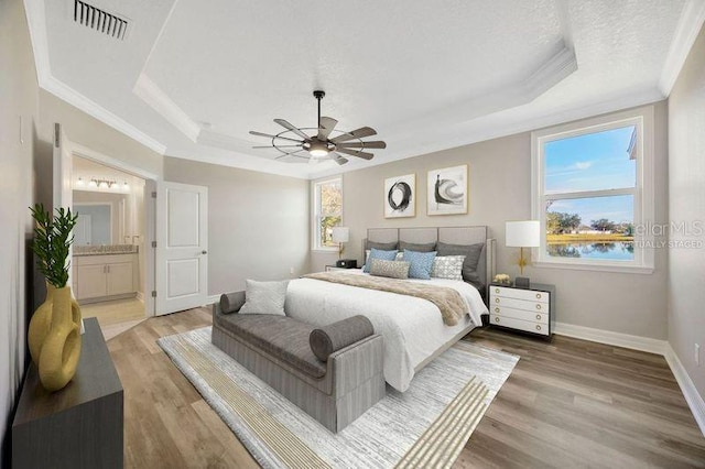 bedroom featuring crown molding, a tray ceiling, and light hardwood / wood-style flooring