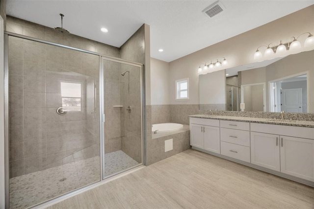 bathroom featuring vanity, independent shower and bath, and wood-type flooring