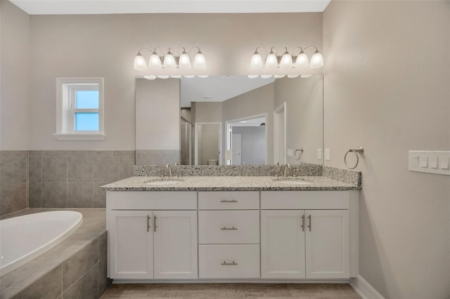 bathroom with a relaxing tiled tub and vanity