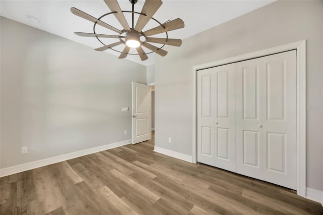 unfurnished bedroom featuring ceiling fan, light hardwood / wood-style floors, and a closet