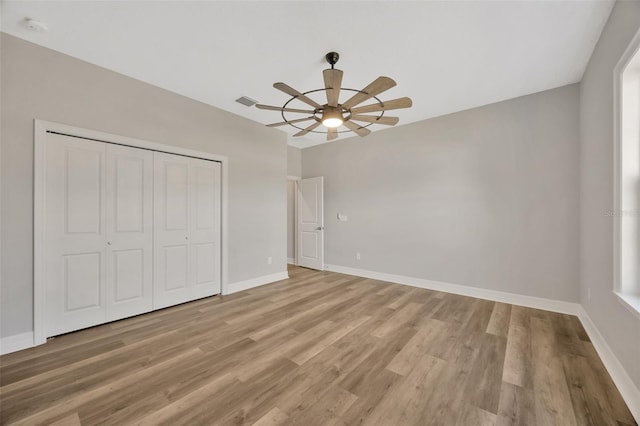 unfurnished bedroom featuring a closet, ceiling fan, and light hardwood / wood-style flooring