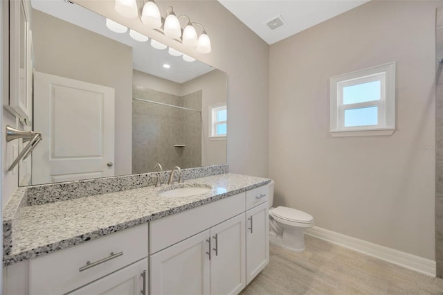 bathroom featuring hardwood / wood-style floors, tiled shower, vanity, and toilet