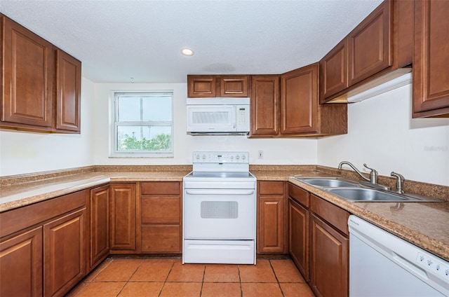 kitchen featuring sink, white appliances, light tile patterned floors, and a textured ceiling