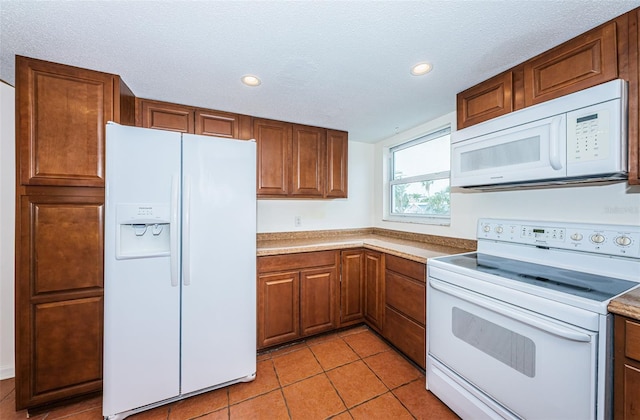 kitchen featuring light tile patterned flooring, a textured ceiling, and white appliances