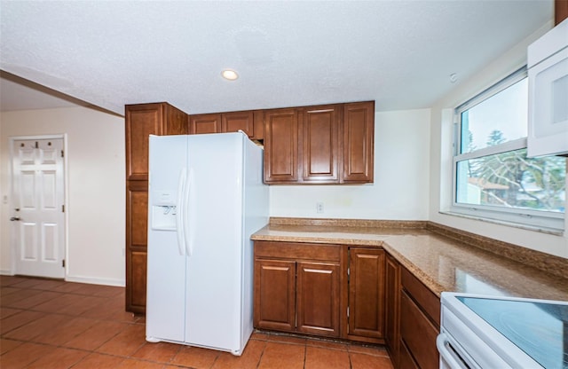 kitchen featuring light tile patterned flooring and white appliances