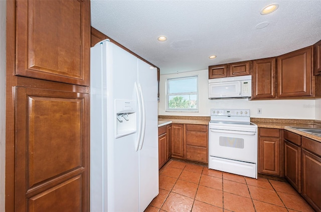 kitchen featuring light tile patterned flooring, a textured ceiling, and white appliances