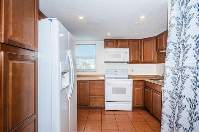 kitchen with sink, light tile patterned floors, a textured ceiling, and white appliances