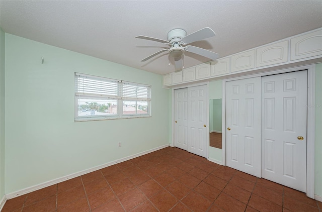 unfurnished bedroom with ceiling fan, dark tile patterned floors, and a textured ceiling