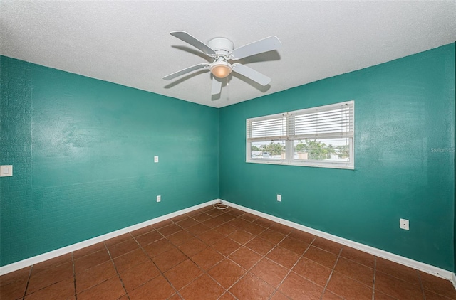 unfurnished room featuring dark tile patterned floors and ceiling fan