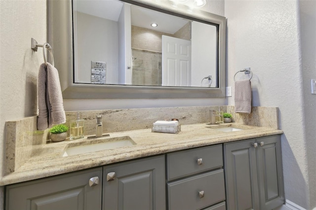 full bathroom featuring double vanity, a textured wall, and a sink