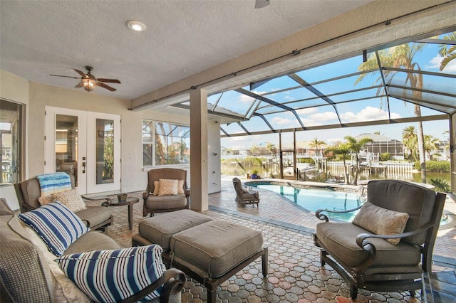 view of patio / terrace with an outdoor living space, a lanai, ceiling fan, and a water view