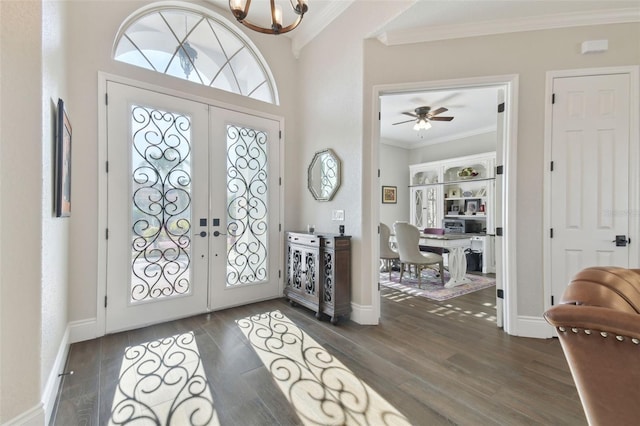 foyer entrance featuring a notable chandelier, french doors, dark wood-style flooring, and ornamental molding