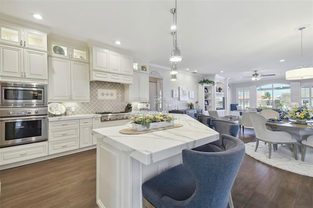 kitchen featuring appliances with stainless steel finishes, white cabinets, backsplash, hanging light fixtures, and ceiling fan