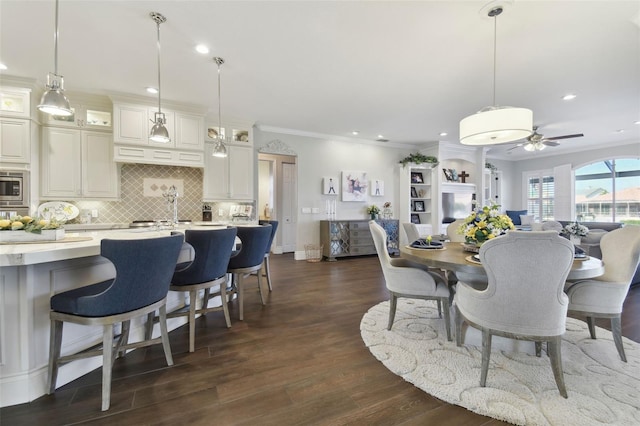 dining area with dark hardwood / wood-style flooring, ornamental molding, and ceiling fan