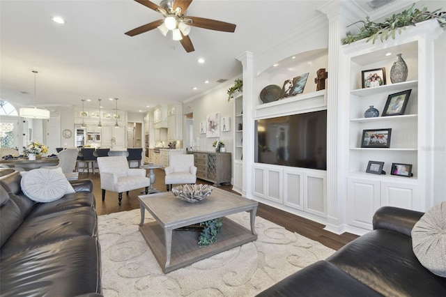 living room featuring hardwood / wood-style flooring, ornamental molding, built in features, and ceiling fan