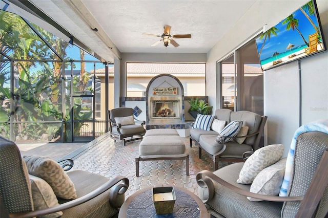 sunroom featuring plenty of natural light, ceiling fan, and a lit fireplace