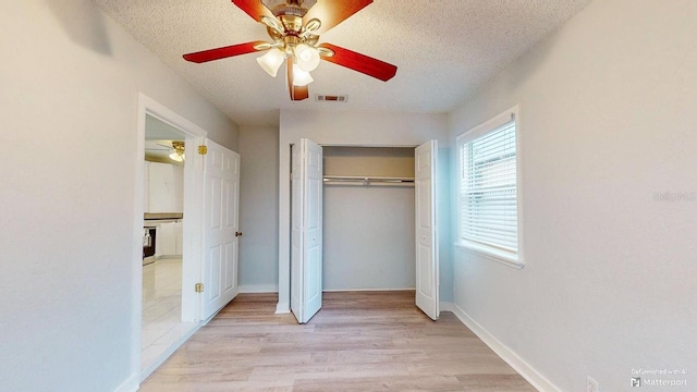 unfurnished bedroom featuring a textured ceiling, ceiling fan, light hardwood / wood-style flooring, and a closet