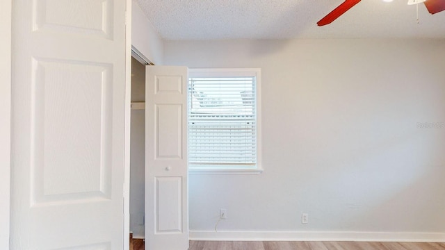 unfurnished bedroom with light wood-type flooring, a textured ceiling, and ceiling fan