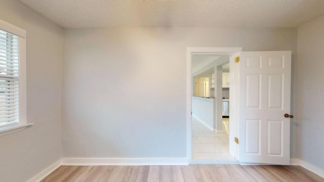 unfurnished room with a textured ceiling and light hardwood / wood-style floors