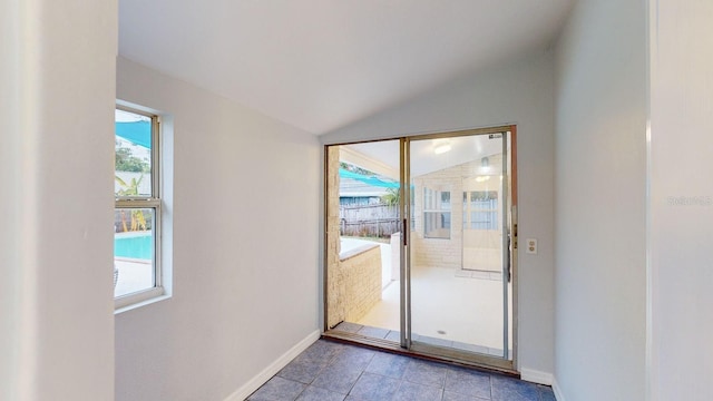 doorway with light tile patterned flooring, lofted ceiling, and plenty of natural light