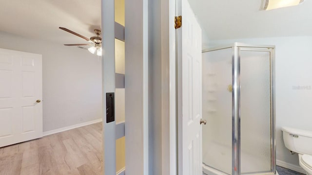 bathroom featuring toilet, a shower with door, ceiling fan, and wood-type flooring