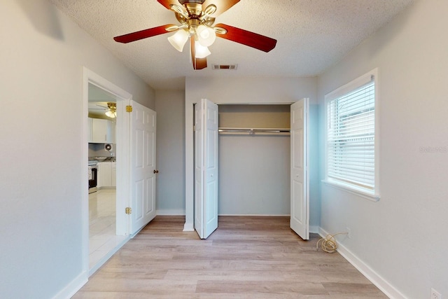 unfurnished bedroom with ceiling fan, light hardwood / wood-style floors, a closet, and a textured ceiling