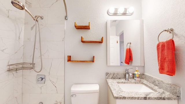 bathroom featuring toilet, vanity, and tiled shower