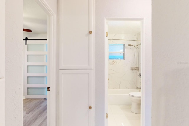 bathroom with toilet, tiled shower / bath combo, built in shelves, and hardwood / wood-style flooring