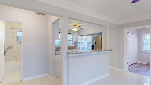 kitchen featuring crown molding, kitchen peninsula, light stone countertops, light tile patterned floors, and stainless steel fridge