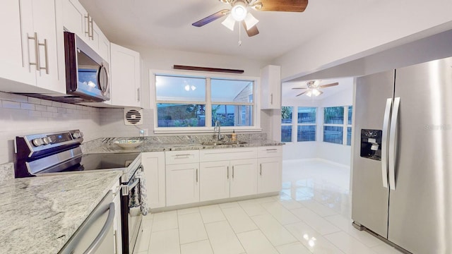 kitchen featuring sink, white cabinets, light stone counters, decorative backsplash, and appliances with stainless steel finishes