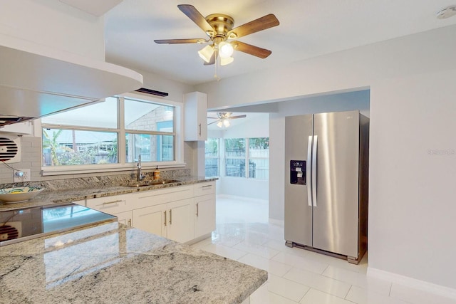 kitchen with light stone counters, stainless steel refrigerator with ice dispenser, white cabinets, light tile patterned flooring, and sink