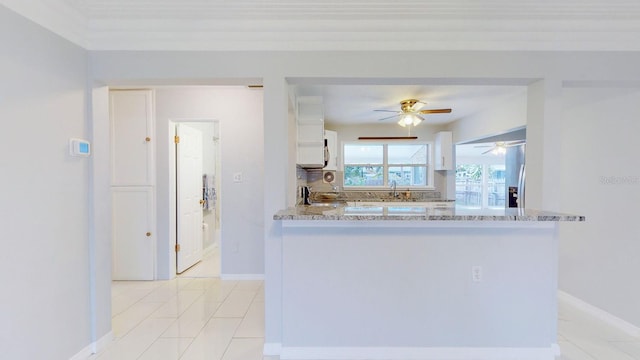 kitchen featuring white cabinets, light tile patterned flooring, kitchen peninsula, decorative backsplash, and light stone countertops