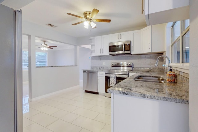 kitchen featuring white cabinets, stainless steel appliances, light stone countertops, sink, and tasteful backsplash