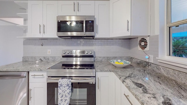 kitchen with white cabinets, appliances with stainless steel finishes, and backsplash