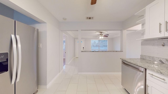 kitchen featuring appliances with stainless steel finishes, tasteful backsplash, white cabinetry, and light stone countertops