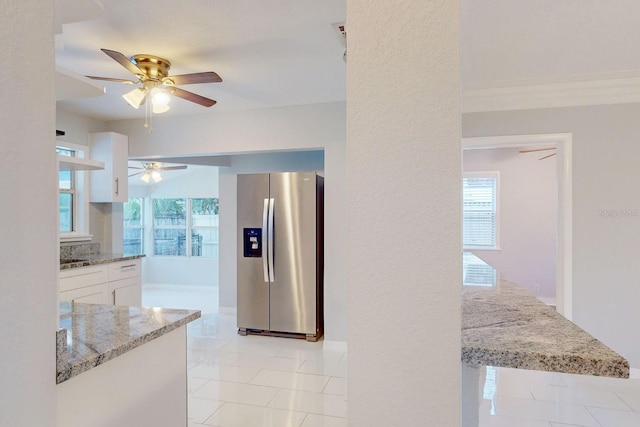 kitchen with white cabinets, a wealth of natural light, light stone counters, and stainless steel refrigerator with ice dispenser