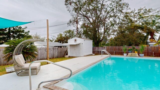 view of pool with a patio and a shed