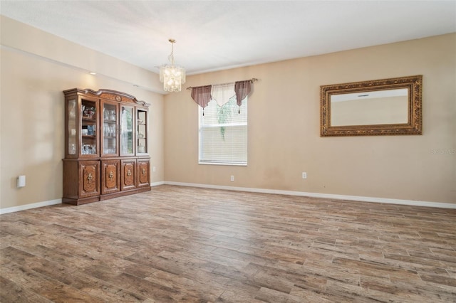 unfurnished room featuring a notable chandelier and hardwood / wood-style flooring