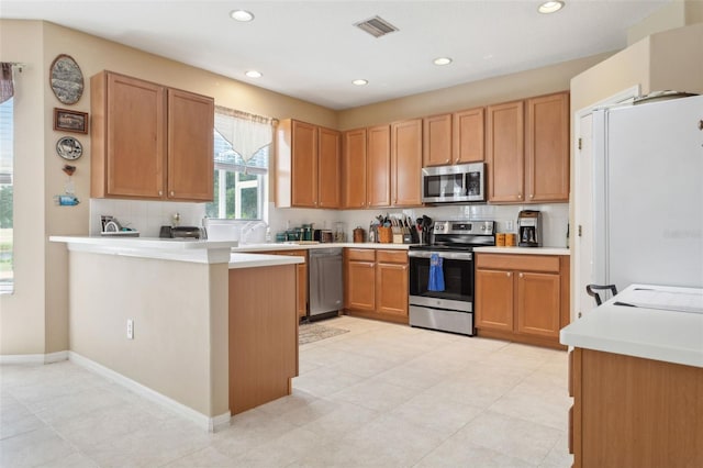 kitchen featuring appliances with stainless steel finishes, kitchen peninsula, and tasteful backsplash