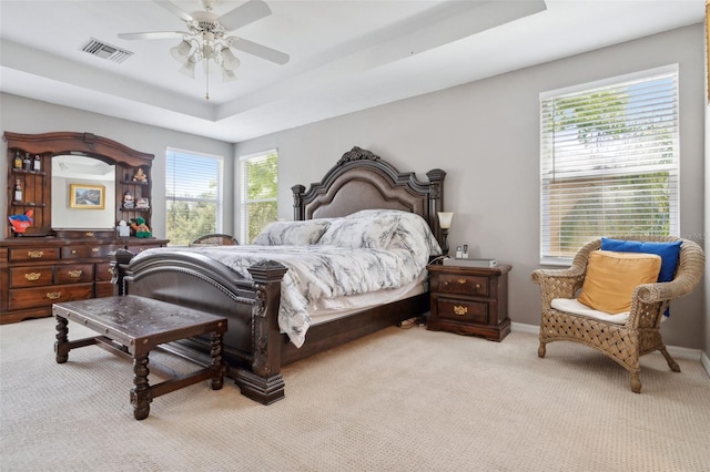 carpeted bedroom featuring ceiling fan and a raised ceiling