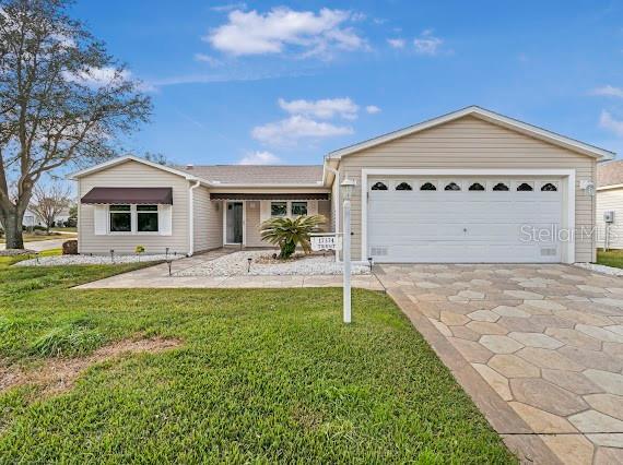 ranch-style house featuring a garage and a front lawn