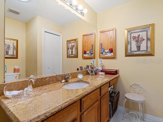 bathroom with a textured ceiling, tile patterned floors, and vanity